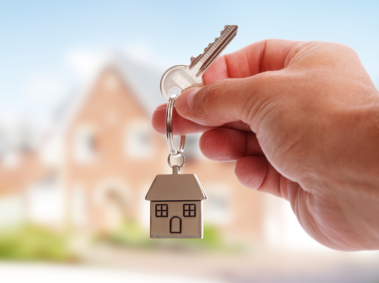 hand holding key with house keychain